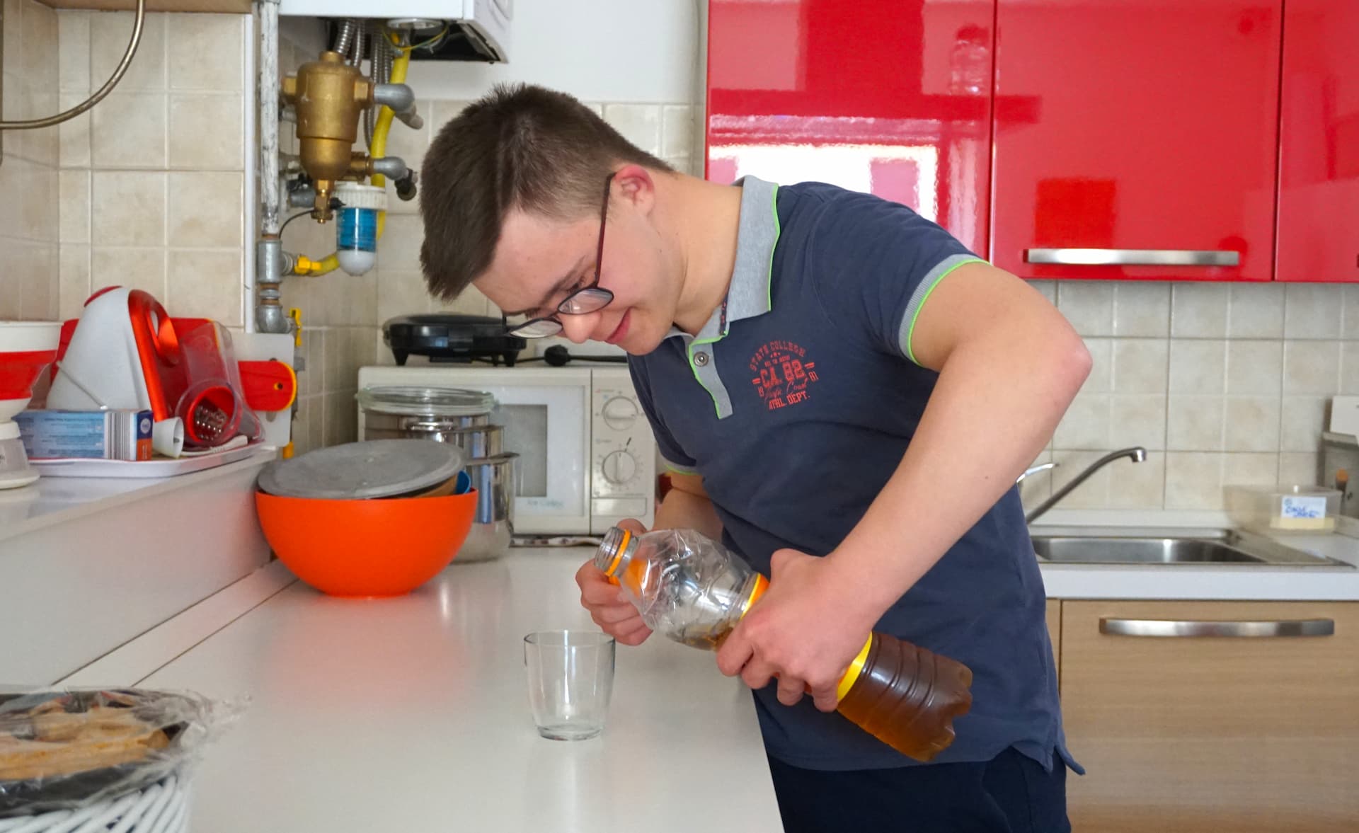 Ragazzo in cucina si versa del tè in un bicchiere