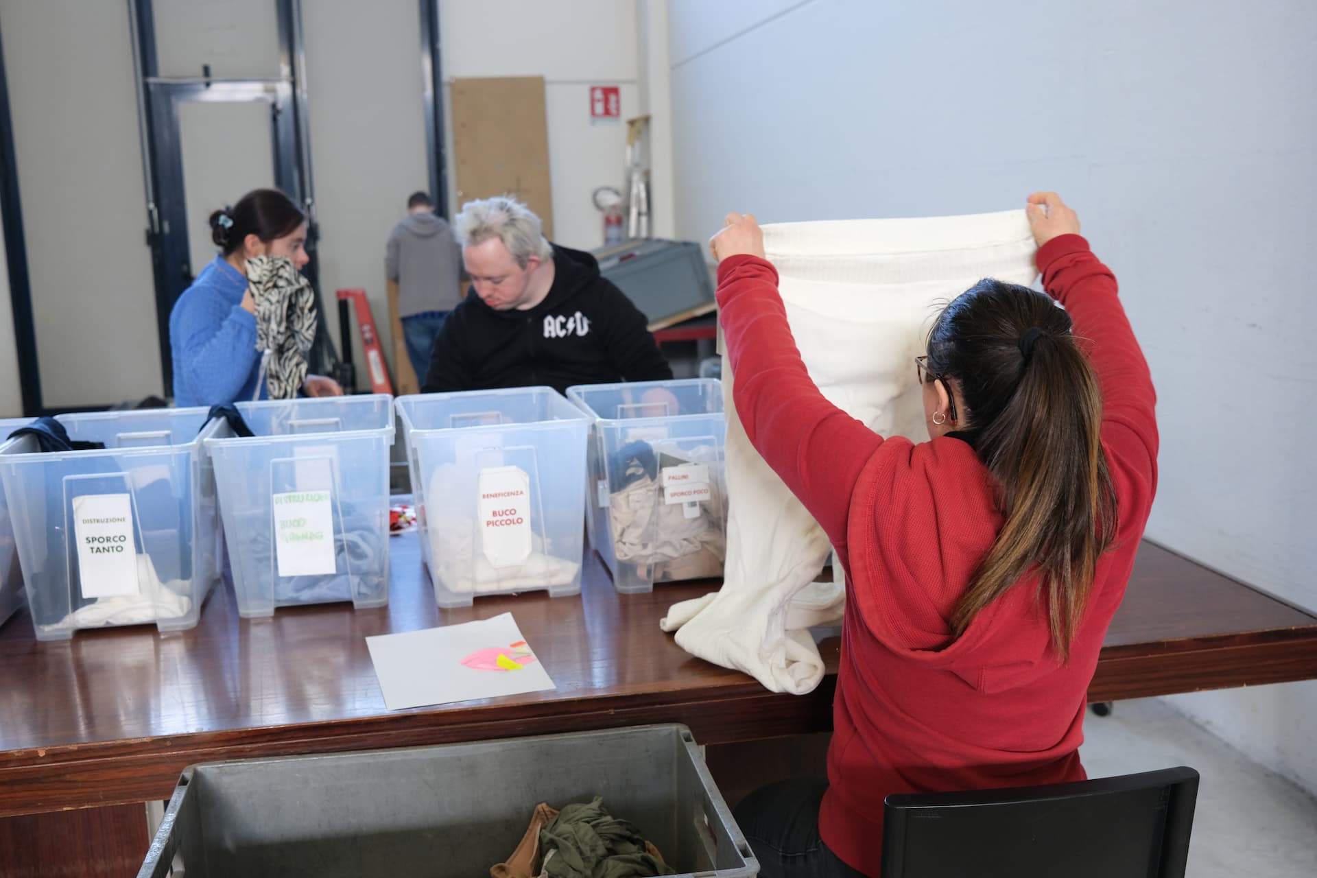 persone svolgono attività di volontariato nell'ordinare capi d'abbigliamento