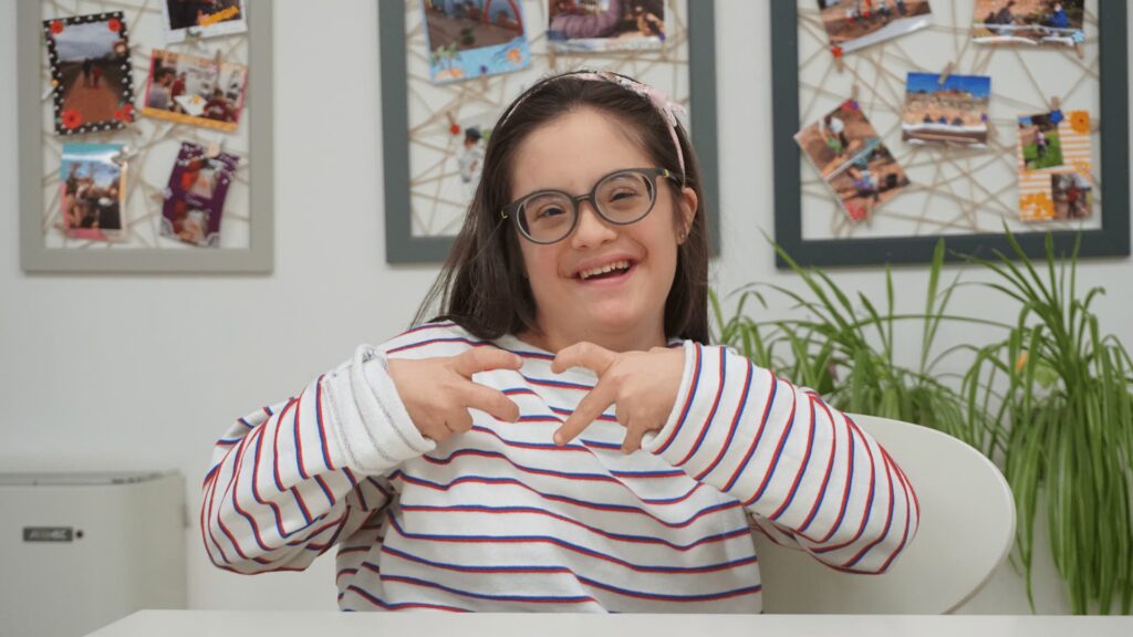 Bambina sorridente fa il simbolo di un cuore con le mani